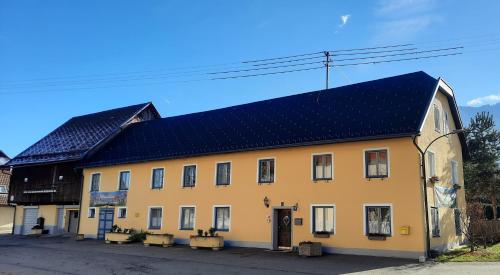 un bâtiment jaune avec un toit noir dans l'établissement B&B Leonhard 7, à Arnoldstein