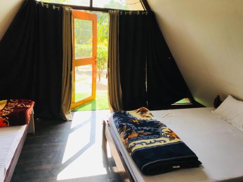 a room with two beds in a tent with a window at Changmai's Inn in Kāziranga