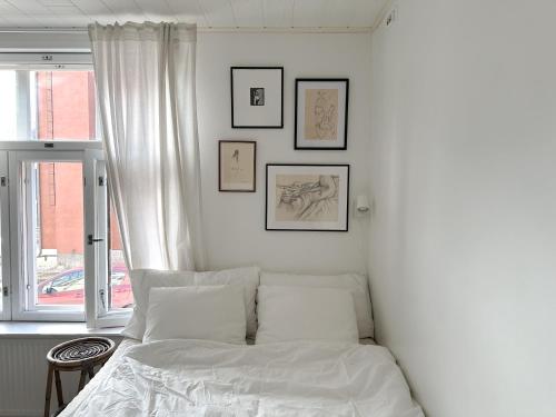 a white bedroom with a bed and pictures on the wall at Wooden house studio with shared garden in Helsinki