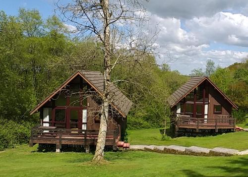 twee houten huisjes in een veld met een boom bij Eastcott Lodges in North Tamerton