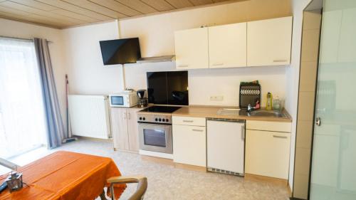 a kitchen with white cabinets and a wooden table at Ferienwohnung und Gästezimmer Reis-Kohl in Mehring