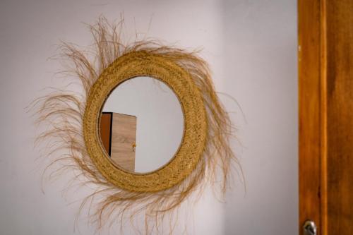 a mirror with a wreath made out of grass on a wall at Soul Surf House Anza in Agadir