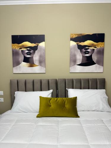 ティラナにあるHorta's homeの帽子を被った女性の絵画2点が飾られたベッドルーム