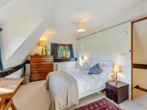 um quarto com uma cama branca e uma cómoda em madeira em Malting Cottage 