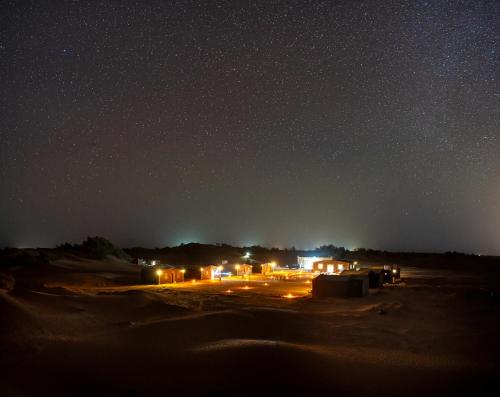 una vista nocturna de un desierto con un cielo estrellado en Taragalte Nomad Camp en Mhamid