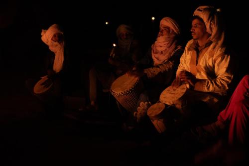 un grupo de personas sentadas en la oscuridad en Taragalte Nomad Camp en Mhamid