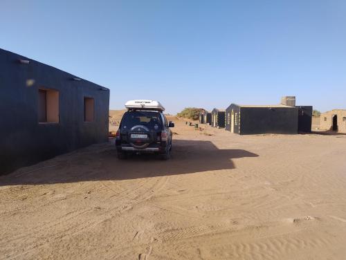 un vehículo estacionado en un camino de tierra en el desierto en Taragalte Nomad Camp en Mhamid