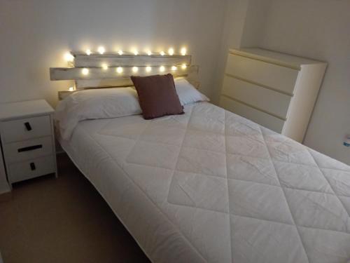 Un dormitorio con una cama blanca con luces. en Apartamento Luna, en Gandía