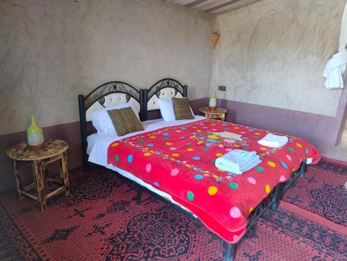 a bedroom with a large bed with a red blanket at Taragalte Nomad Camp in Mhamid