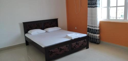 a bedroom with a bed with white sheets and a window at Saragama Apartment in Kurunegala
