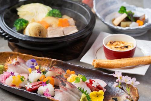 una mesa con un plato de comida y un tazón de comida en KAMENOI HOTEL Genkainada en Kitakyushu