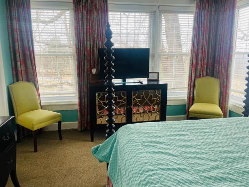 a bedroom with a bed and two chairs and a television at Excelsior at the Manor House in Clemmons