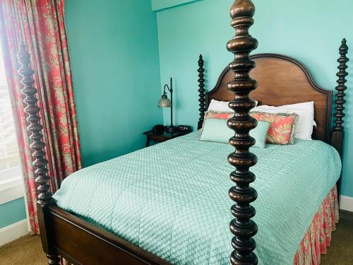 a bed in a blue room with a wooden frame at Excelsior at the Manor House in Clemmons
