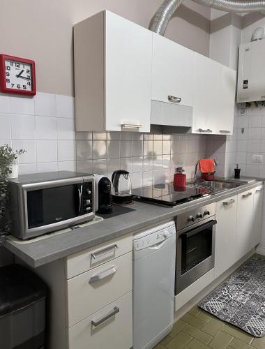a kitchen with white cabinets and a microwave at Monolocale Comodo alla Metro in Turin