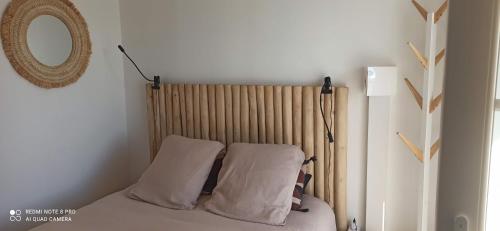 a bedroom with a bed with two pillows and a mirror at Chez isa in Barbâtre