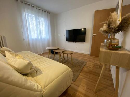 a living room with a bed and a table and a television at Le Coty - Appartement -St Marie des champs in Sainte-Marie-des-Champs