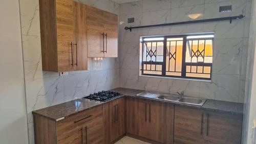a kitchen with wooden cabinets and a sink and a window at Luxury 3 Bedroom Self Catering Apartment- Masvingo in Nyanda
