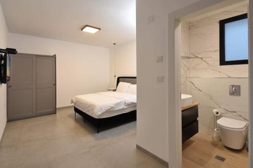 - une chambre avec un lit et une salle de bains pourvue d'un lavabo dans l'établissement וילה אליה, à Migdal