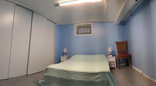 Cette chambre comprend un lit et un mur bleu. dans l'établissement Chambre dans maison prés du stade de France et piscine olympique, à Franconville