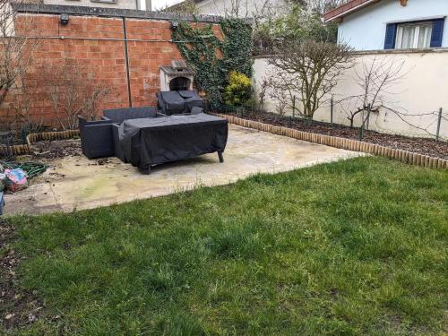 un patio avec une table et des chaises dans une cour dans l'établissement Chambre dans maison prés du stade de France et piscine olympique, à Franconville
