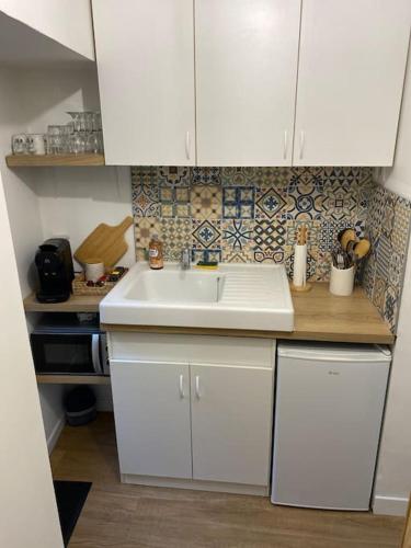 La cuisine est équipée de placards blancs et d'un évier blanc. dans l'établissement Maison de charme, à Ambleny