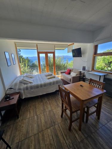 a bedroom with a bed and a table and a couch at Melipal Schuss ARG41 in San Carlos de Bariloche