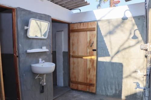 baño con lavabo y puerta de madera en Mr Fisherman, en Arugam Bay