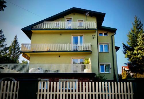a yellow house with a white fence in front of it at Villa Romano in Kielce
