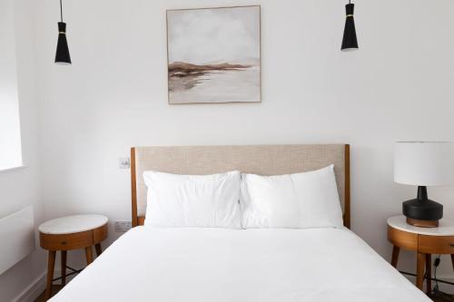 a bedroom with a white bed and two tables at Luxury 2 Bedroom Huge Duplex Covent Garden Holborn in London