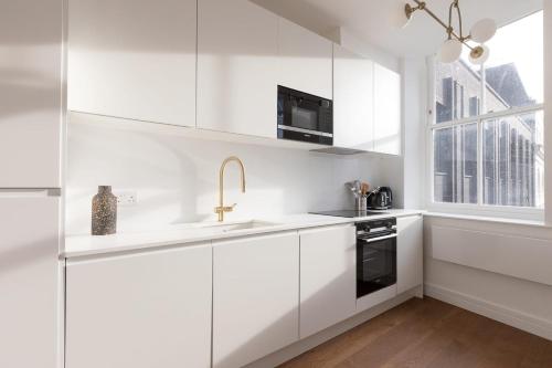 a white kitchen with white cabinets and a sink at Luxury 2 Bedroom Huge Duplex Covent Garden Holborn in London