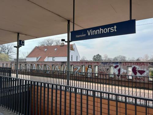 a sign at a train station with graffiti on a wall at Durmaz Hotel in Hannover