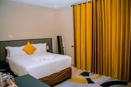 a bedroom with a bed and yellow curtains at Sewelo inn guesthouse in Maun
