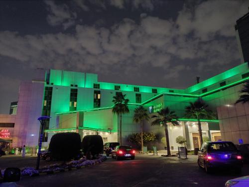 un edificio verde con macchine parcheggiate di fronte di Holiday Inn Riyadh Al Qasr, an IHG Hotel a Riyad