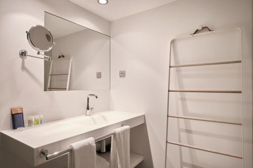 Baño blanco con lavabo y espejo en Mercer House Bòria BCN, en Barcelona