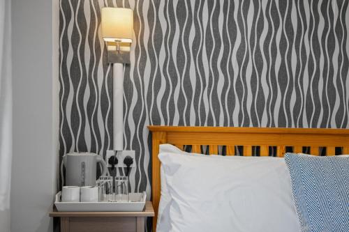 a bed with a white pillow next to a wall at Queensferry Guest house in Rosyth