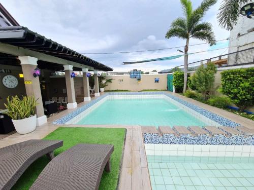 a swimming pool with two chairs next to a building at Palazzo 1 HotSpring,3Bedrooms 35to40pax, Pansol Calamba in Pansol
