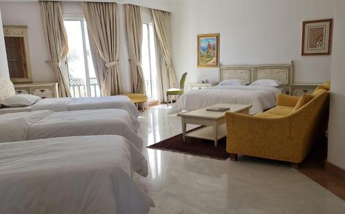 a hotel room with four beds and a table and chairs at Beit Al-Madina in Al ‘Uyūn