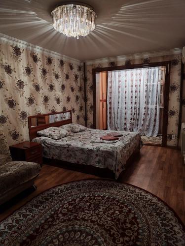 a bedroom with two beds and a window and a chandelier at Квартира 2х комнатная in Shymkent
