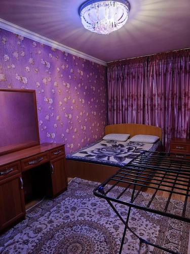 a bedroom with a bed and a tv and purple walls at Квартира 2х комнатная in Shymkent