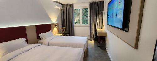 a hotel room with two beds and a flat screen tv at Anaïs Hôtel Bourges Nord Saint-Doulchard in Bourges