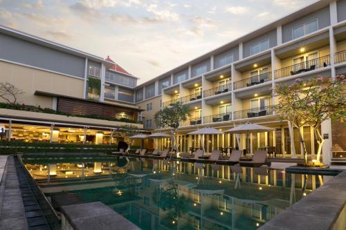 a hotel with a pool in front of a building at The Kana Kuta Hotel in Kuta