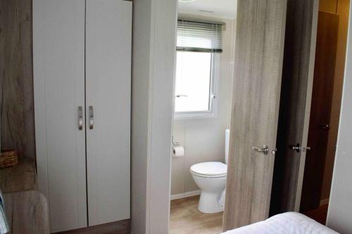 a bathroom with a white toilet and a window at Scottish Holiday Home in Ardeer Square