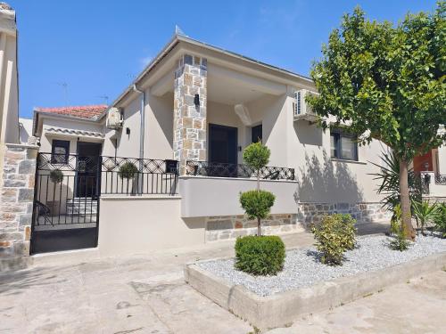 a white house with a balcony and a tree at Volos Guesthouse Chrysa in Volos