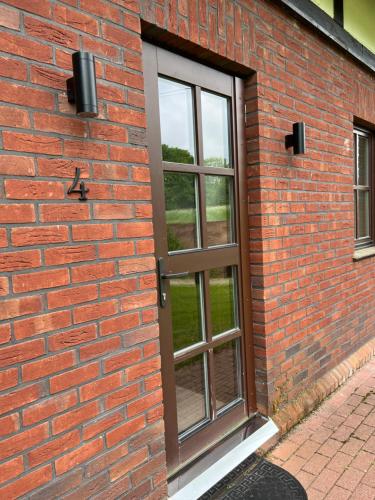 a door on a brick wall with a window at Senasis Rambynas in Lumpėnai
