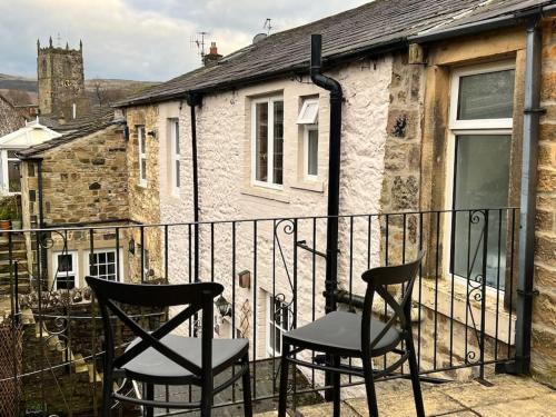 two chairs sitting on the balcony of a house at Arthur’s Cottage in Skipton