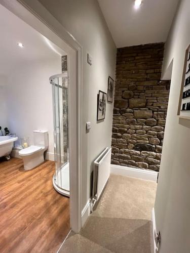 a room with a bathroom with a stone wall at Arthur’s Cottage in Skipton