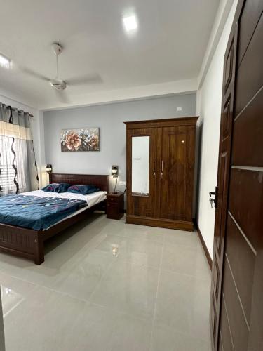 a bedroom with a bed and a wooden cabinet at Matheera Holiday Home in Jaffna