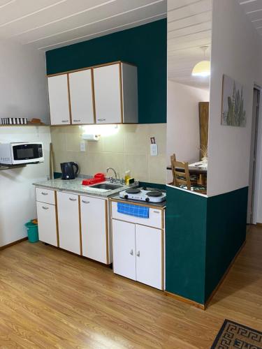 a kitchen with white cabinets and a green wall at Apartamento El Hornero in San Rafael