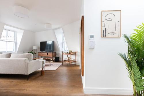 a living room with a couch and a tv at Luxury 2 Bedroom Duplex Penthouse Covent Garden Holborn in London