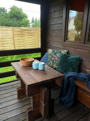 una mesa de madera con tazones y tazas en un porche en DOMKI LETNISKOWE KOMAŃCZA, en Komańcza